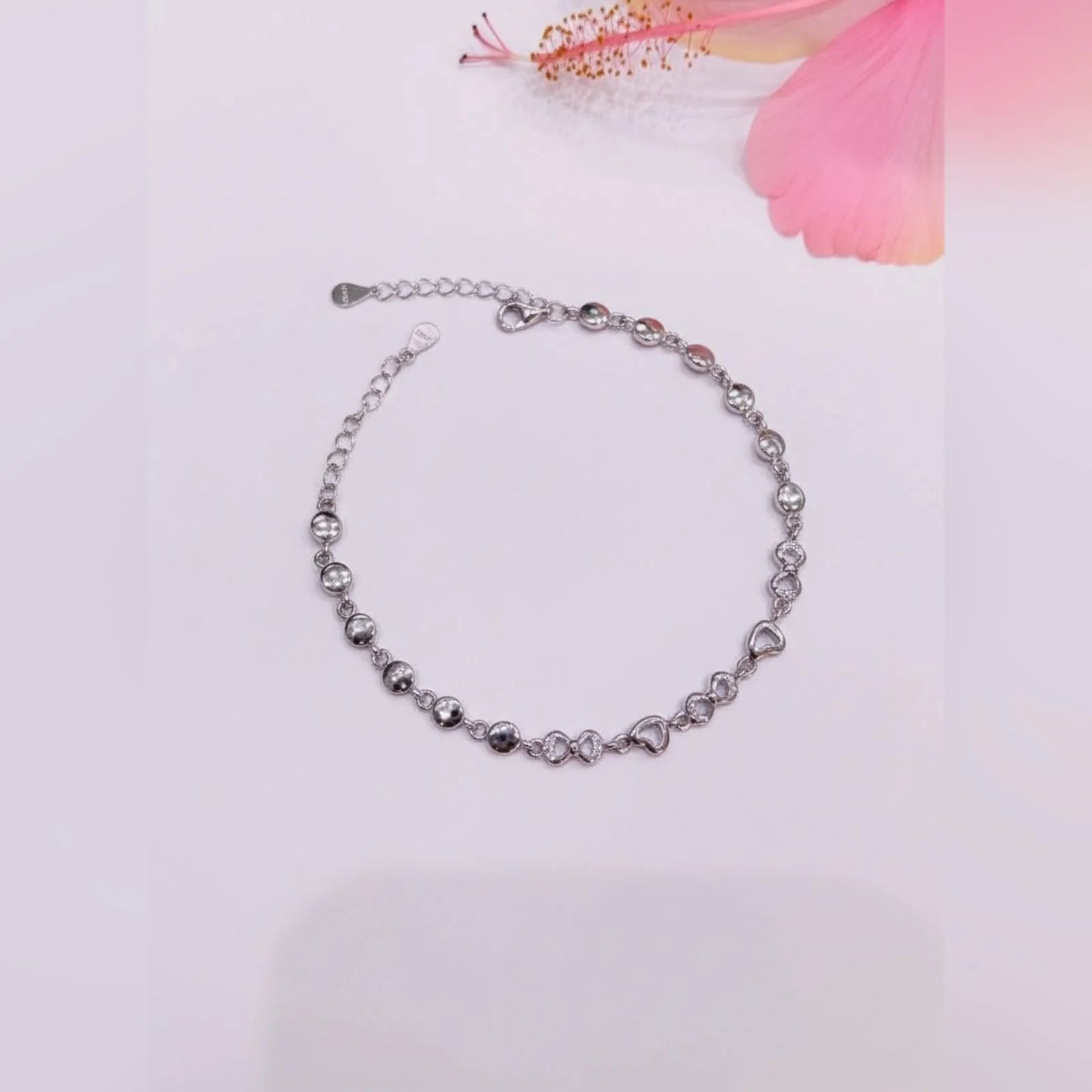 Silver bracelet with heart-shaped beads on a light pink background