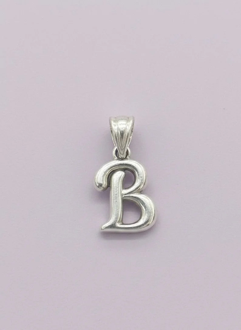 Silver 'B' pendant on a light purple background