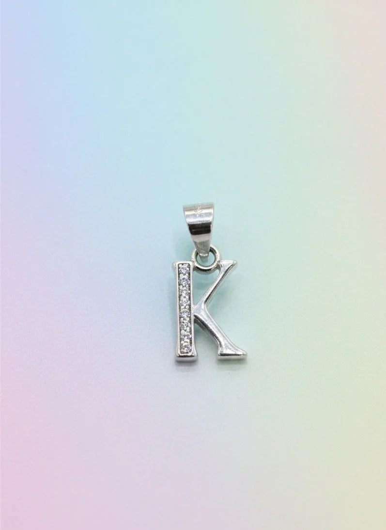 Silver 'K' pendant on a pastel gradient background