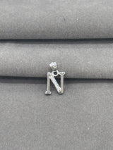Silver letter 'N' pendant on a gray fabric background