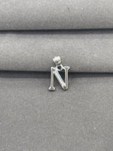 Silver letter 'N' pendant on a gray fabric background