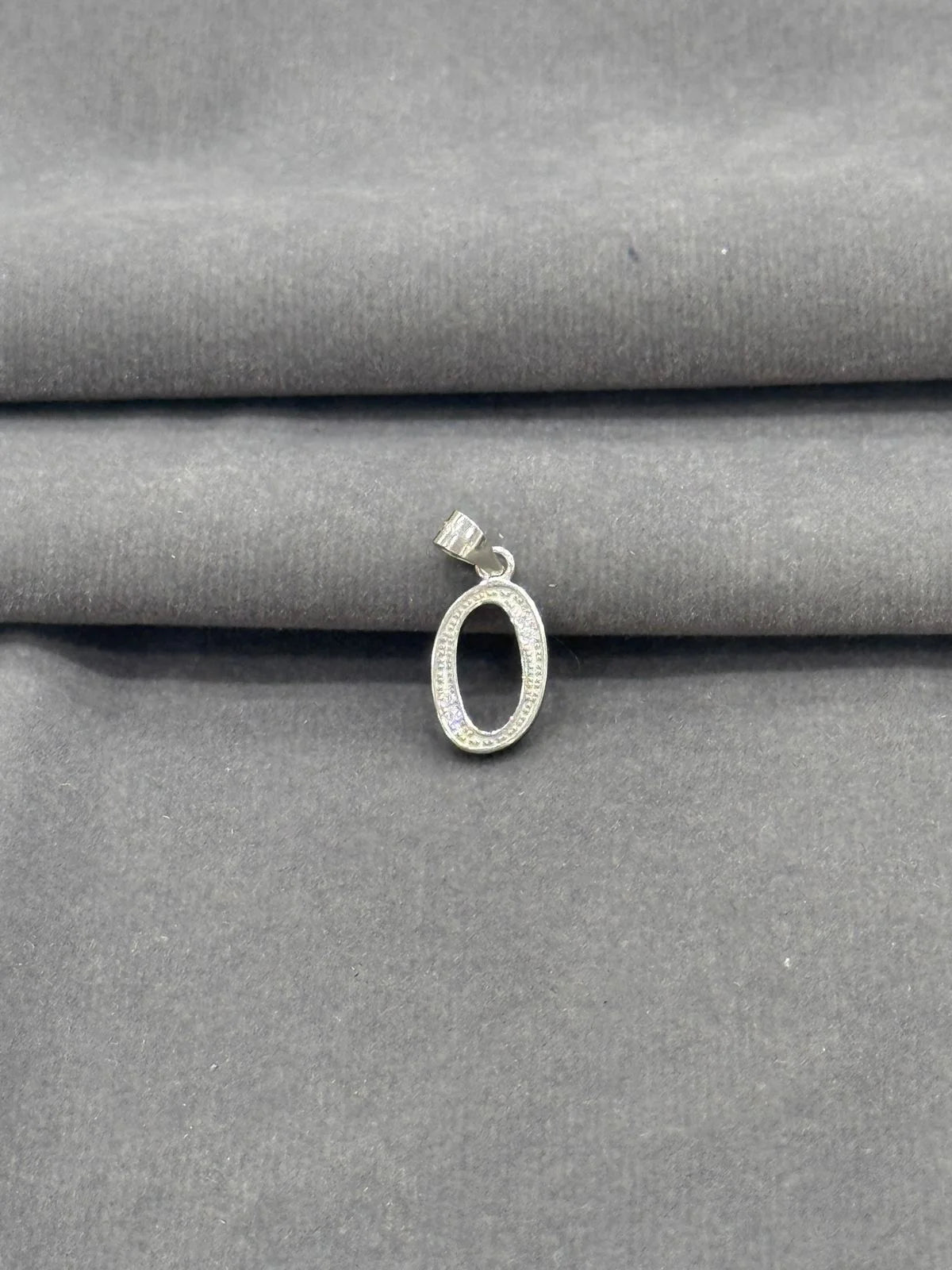 Silver pendant on a gray fabric background
