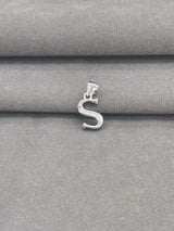 Silver 'S' pendant on a gray fabric background