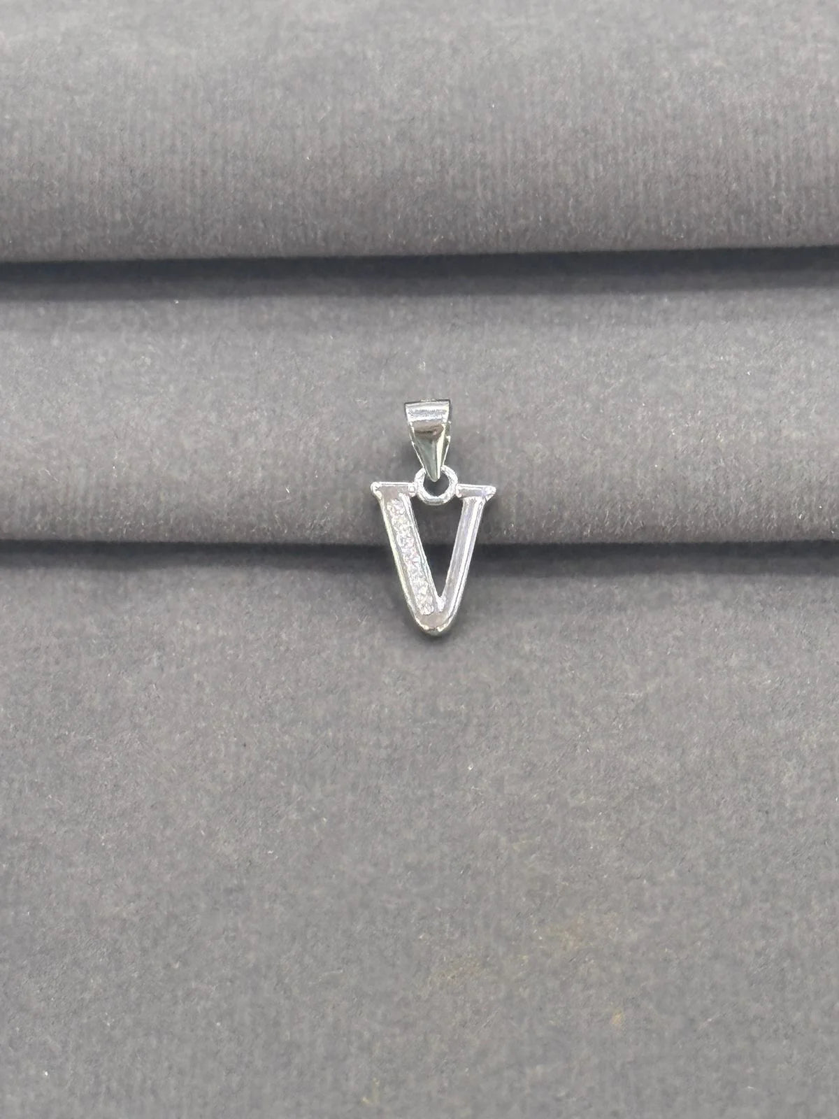 Silver 'V' shaped pendant on a gray fabric background