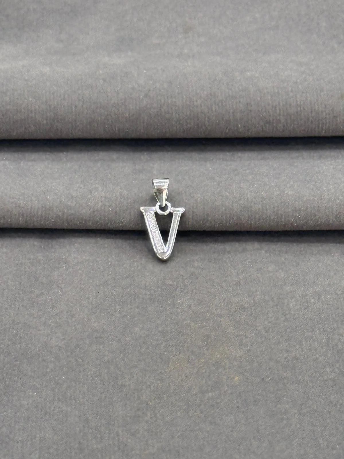 Silver 'V' shaped pendant on a gray fabric background