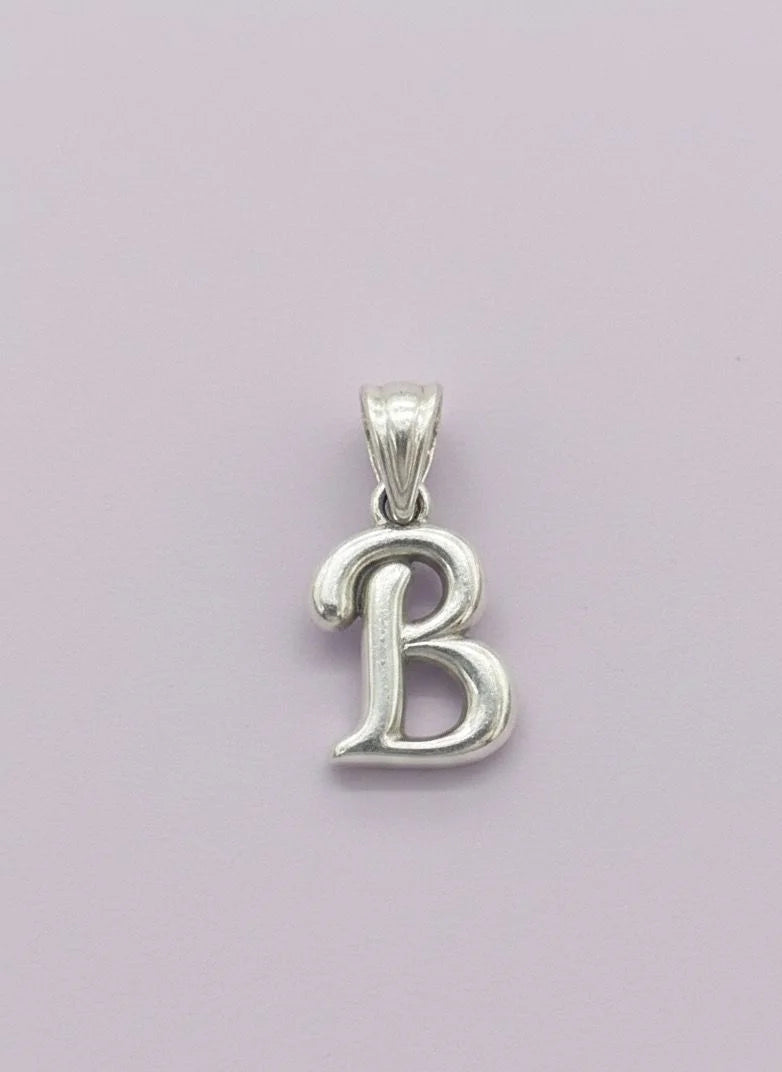 Silver 'B' pendant on a light purple background