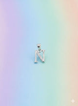 Silver necklace with a letter 'N' pendant on a pastel gradient background