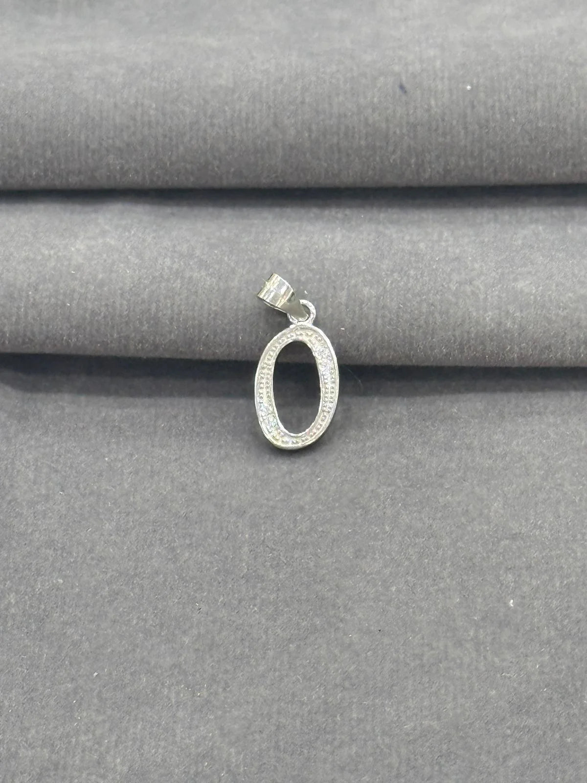 Silver pendant on a gray fabric background