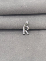 Silver 'R' letter pendant on a gray fabric background