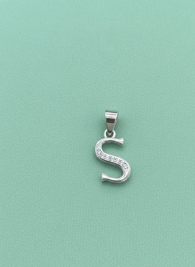 Silver 'S' pendant with clear stones on a light green background
