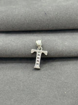 Silver 'T' shaped pendant on a gray fabric background