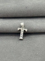 Silver 'T' letter pendant on a gray fabric background
