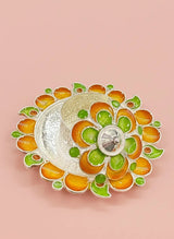 Decorative silver bowl with orange and green floral patterns on a pink background