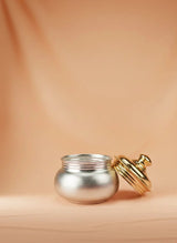 Silver pot with a gold lid on a beige background