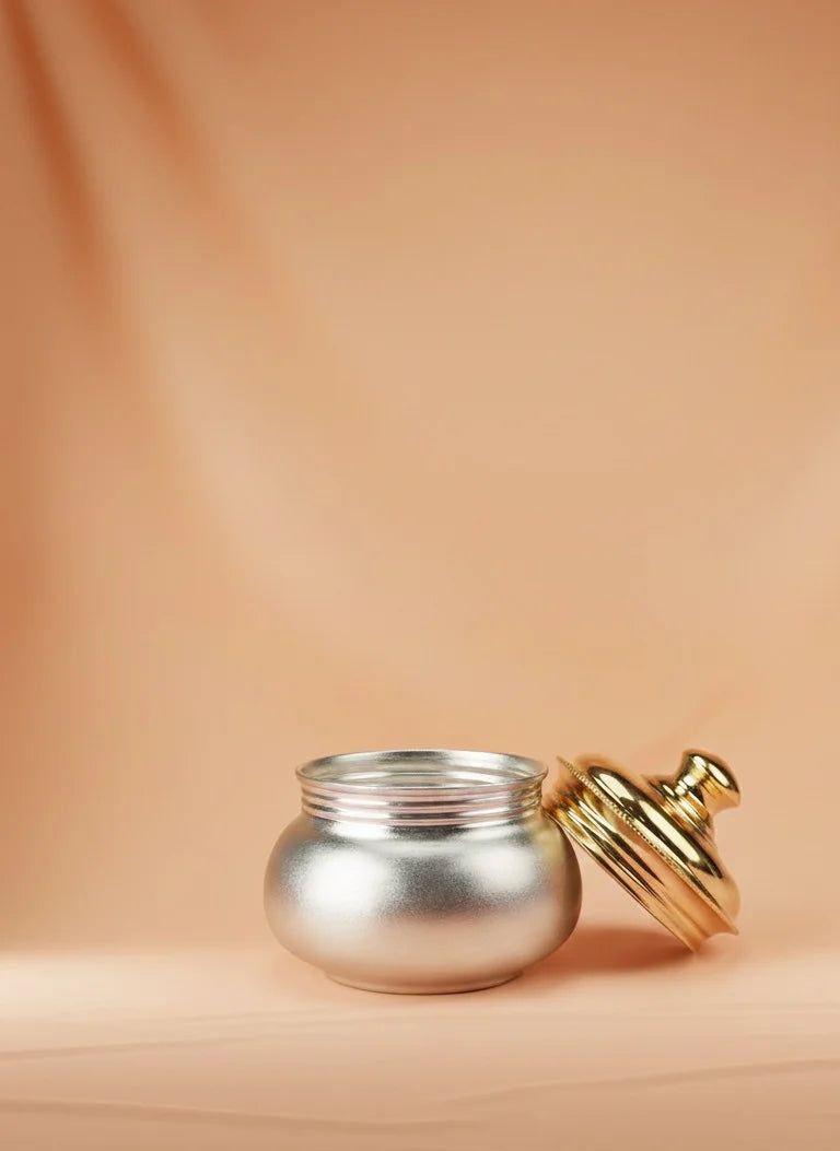 Silver pot with a gold lid on a beige background