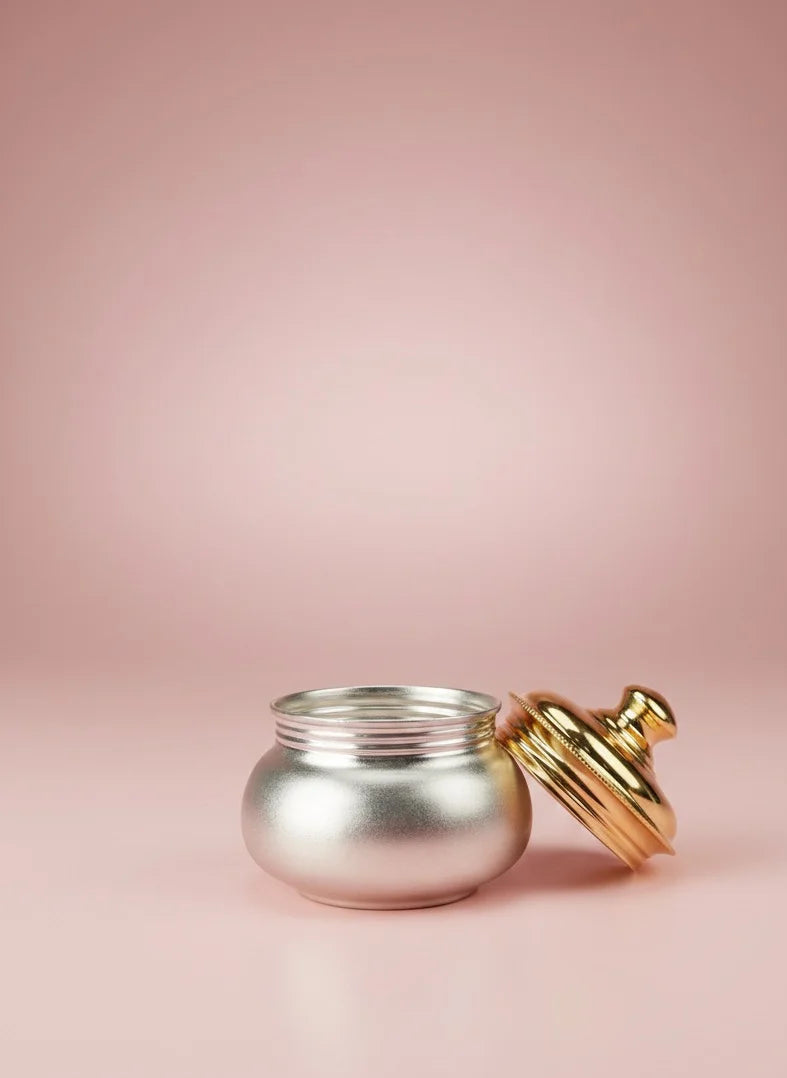 Silver jar with a gold lid on a pink background