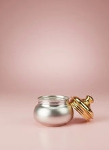 Silver jar with a gold lid on a pink background