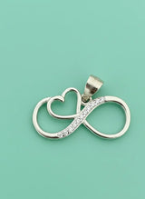 Silver pendant with infinity symbol and heart on a light green background