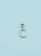 Silver moon-shaped  C pendant with embedded stones on a light blue background