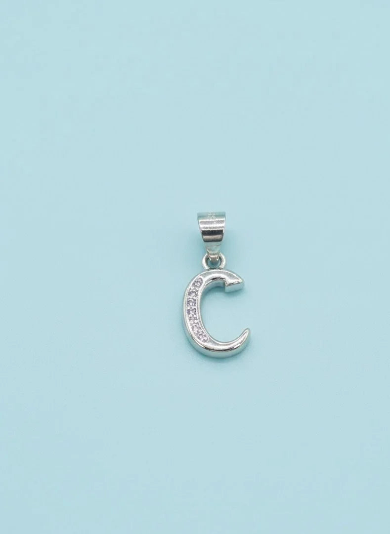 Silver moon-shaped  C pendant with embedded stones on a light blue background