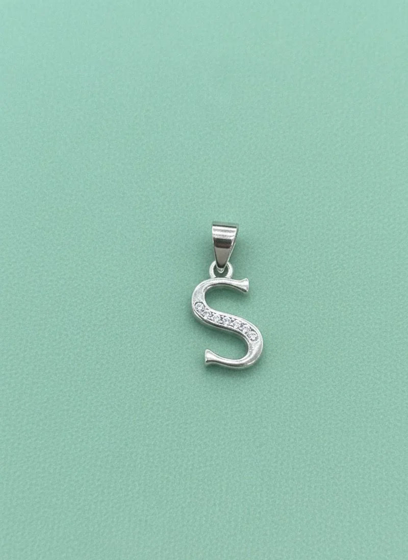 Silver 'S' pendant with clear stones on a light green background
