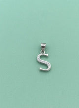 Silver 'S' pendant with clear stones on a light green background