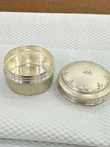 Silver jar with lid on a textured white surface
