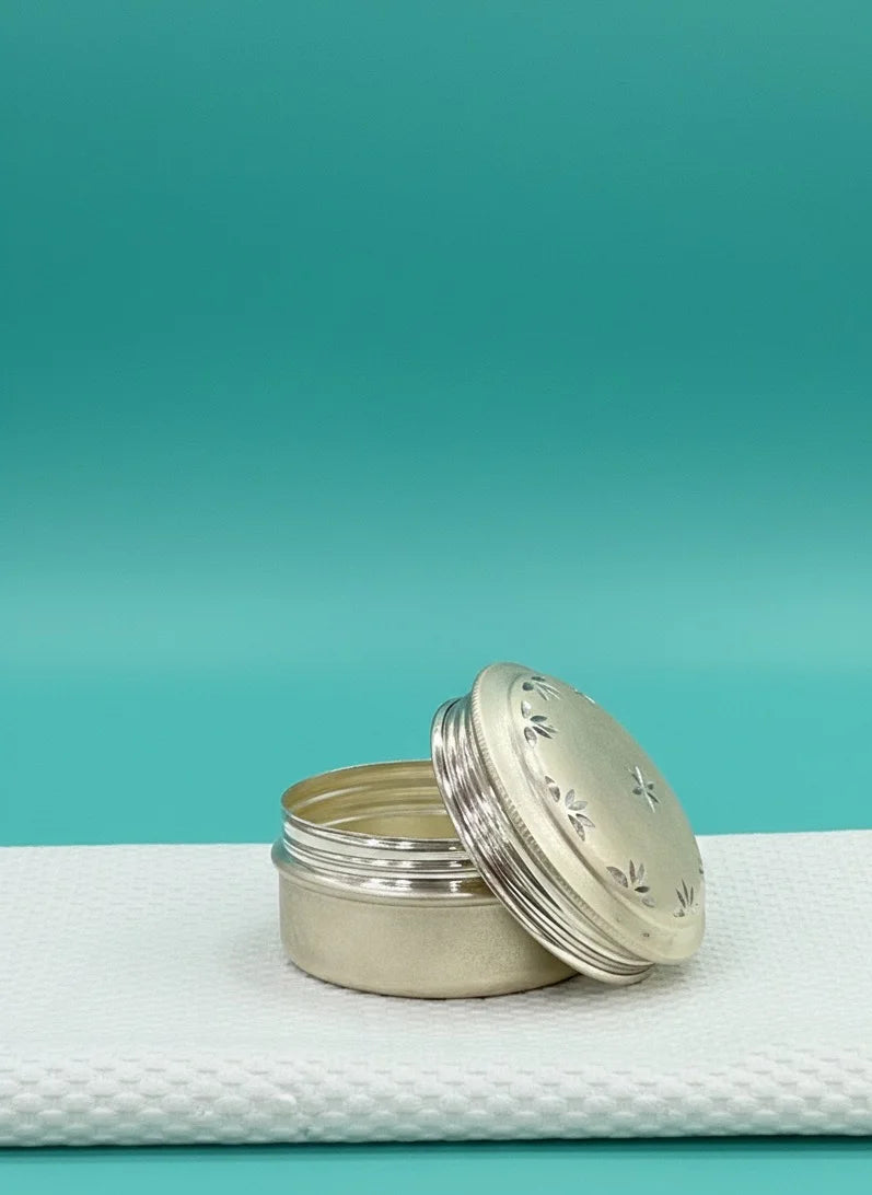 Two silver containers on a textured white surface with a teal background