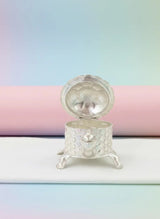 Small decorative silver box on a pastel background