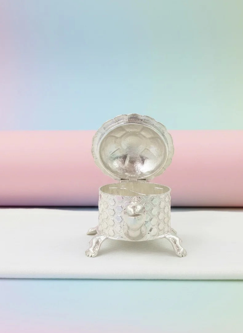 Small decorative silver box on a pastel background
