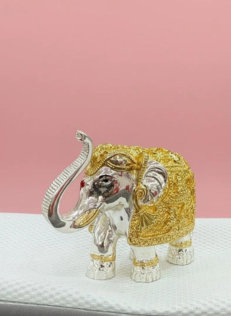 Decorative elephant figurine with gold and silver finish on a pink background