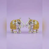 Decorative elephant figurines with gold and silver accents on a light purple background