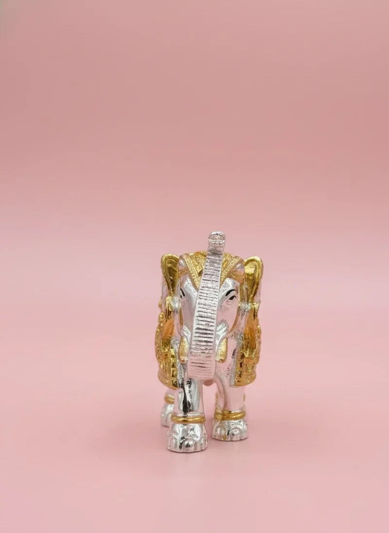 Decorative elephant figurine in silver and gold on a pink background