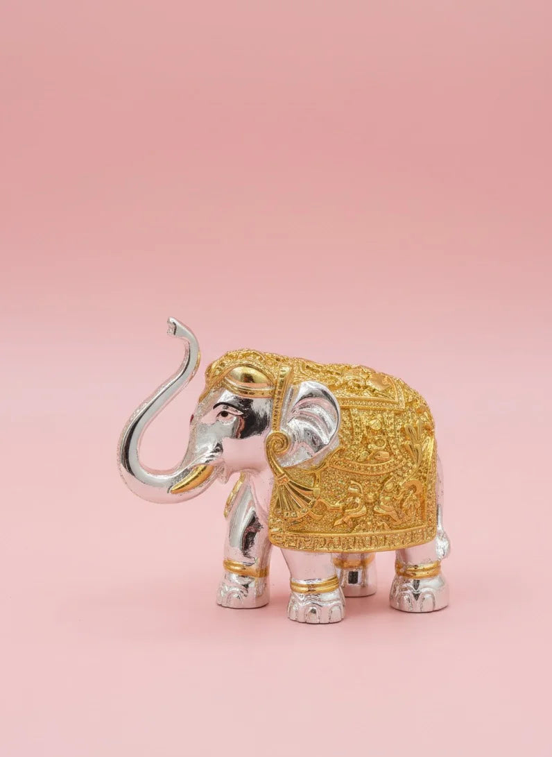 Decorative elephant figurine with gold and silver details on a pink background