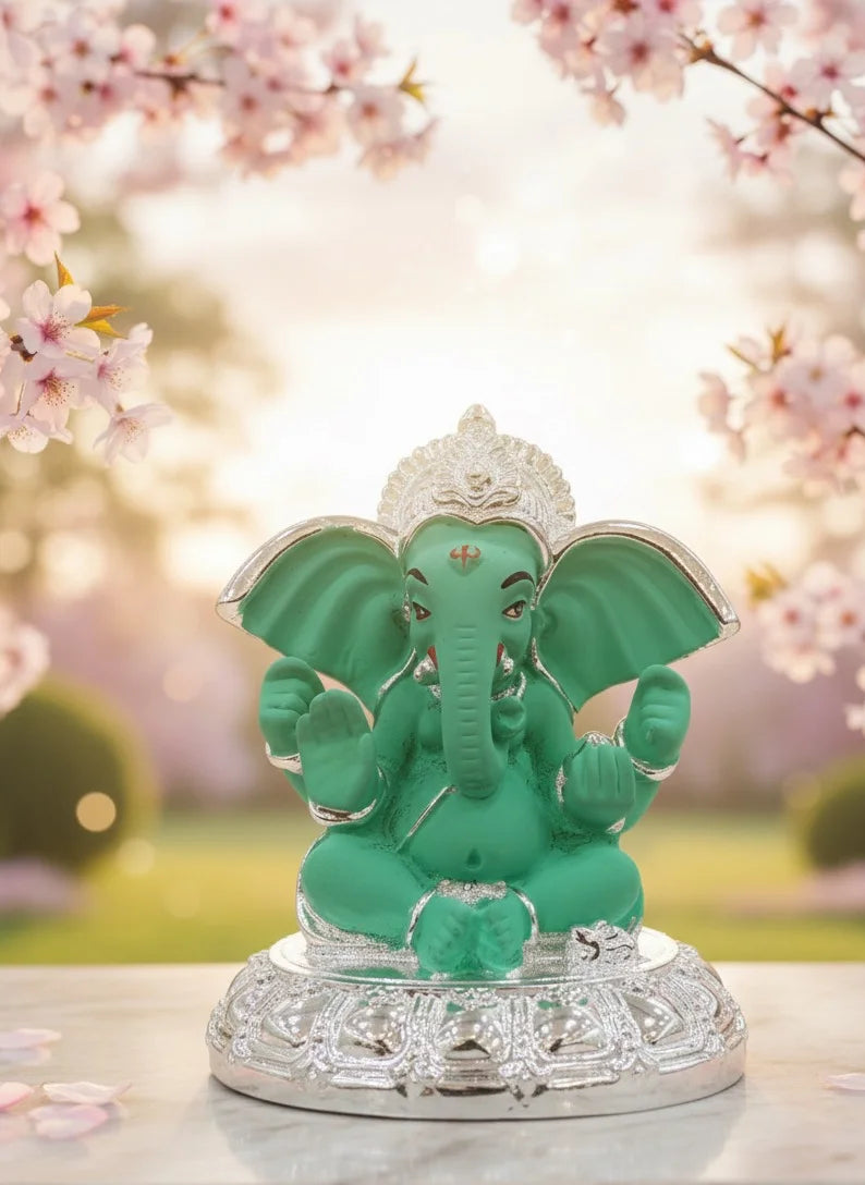 Green elephant statue on a decorative base with cherry blossoms in the background