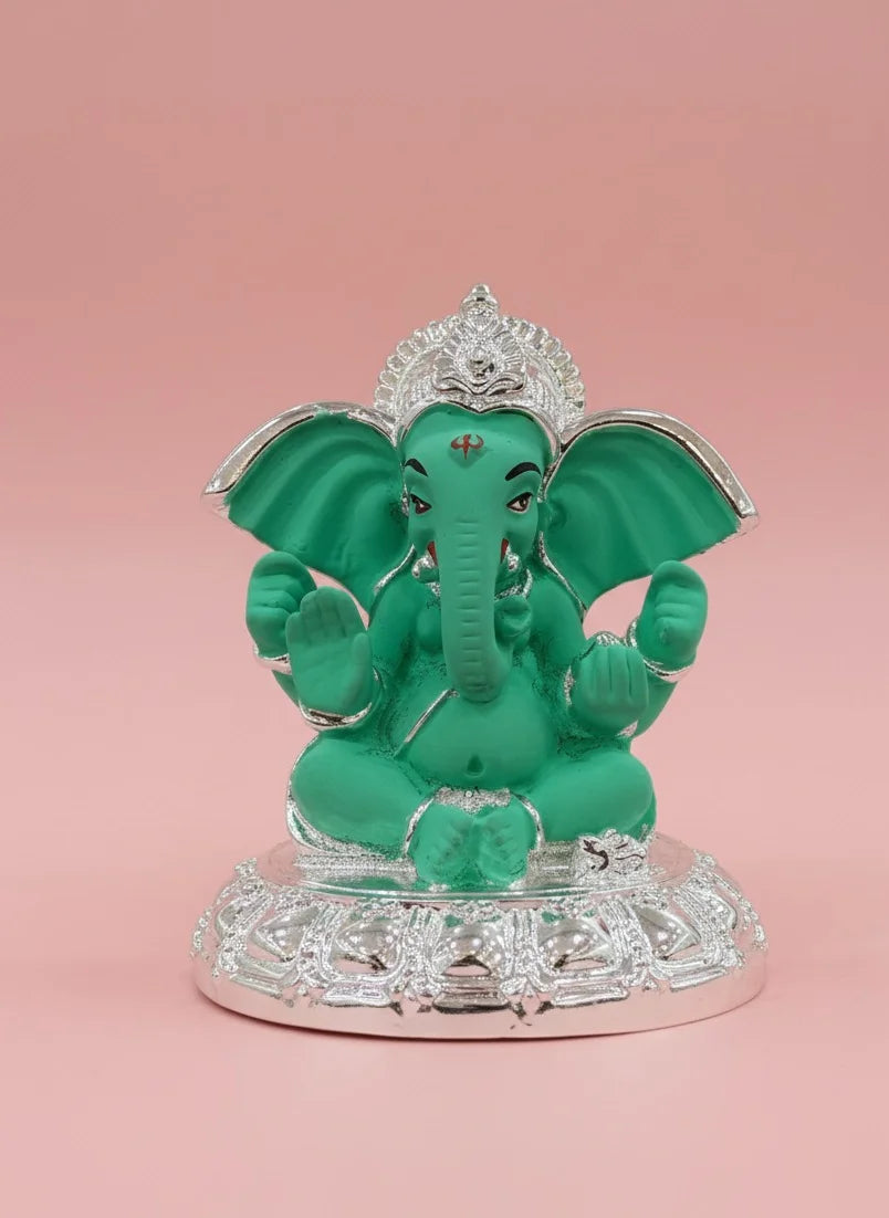 Green elephant statue with silver accents on a pink background