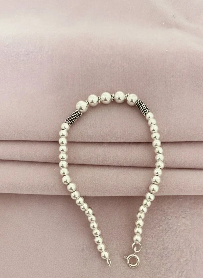 Silver ball bracelet on a pink fabric background