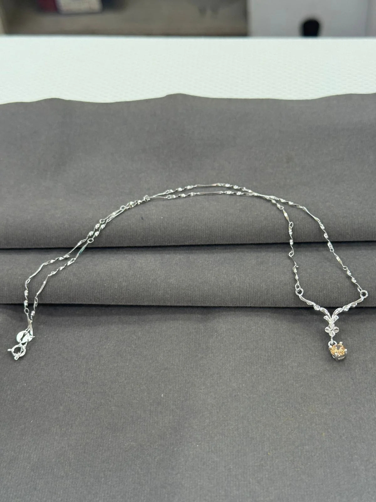 Silver necklace with charms on a gray surface