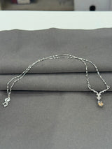 Silver necklace with charms on a gray surface