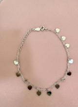 Silver bracelet with heart-shaped charms on a pink background