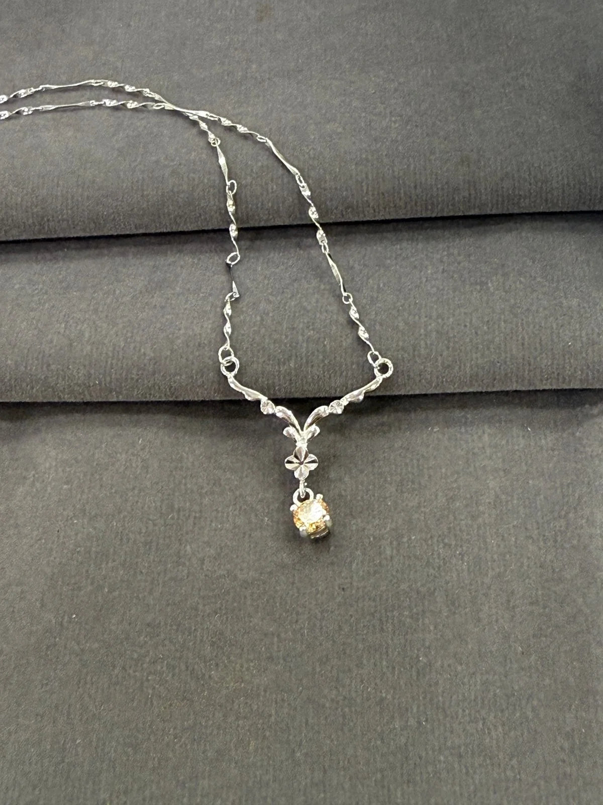 Silver necklace with a small pendant on a gray surface