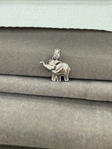 Silver elephant pendant on a stack of gray fabric