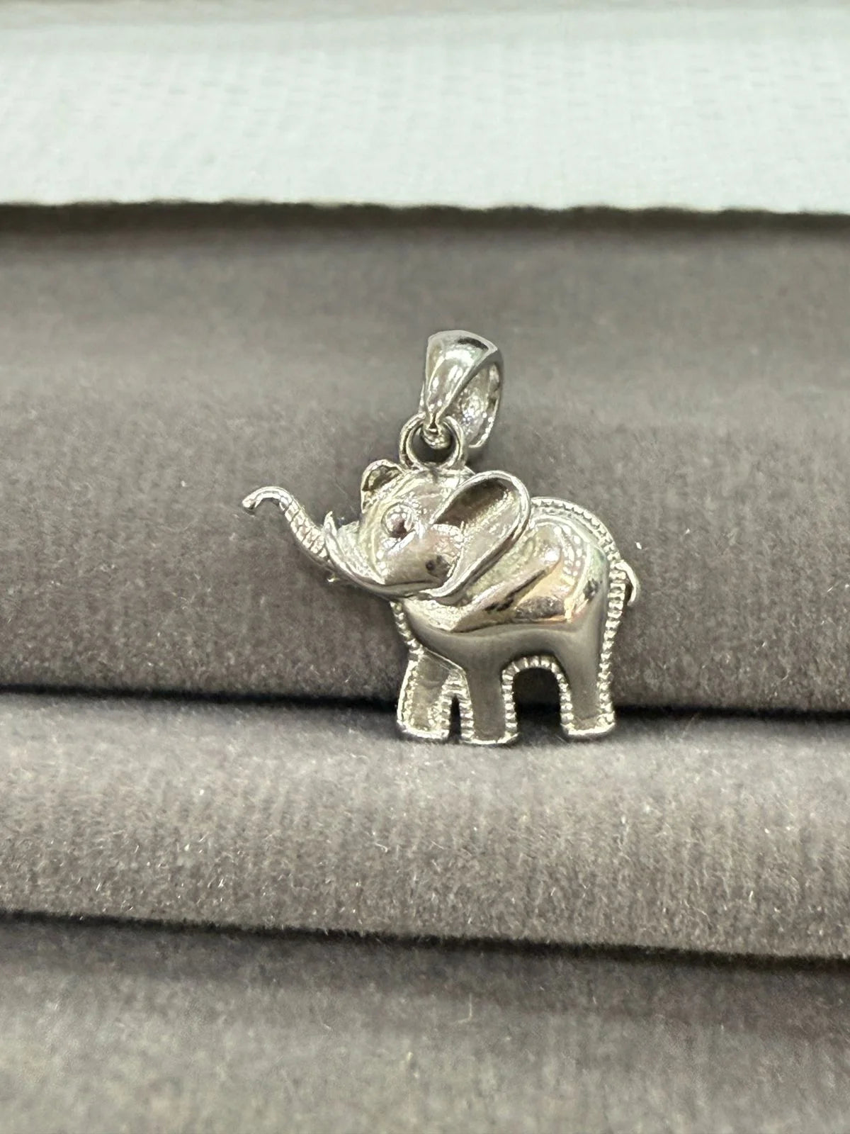 Silver elephant pendant on a gray fabric background