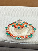 Decorative metal lid with colorful patterns on a textured surface