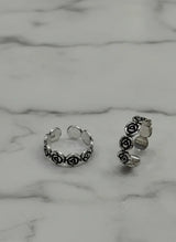 Silver toe rings with floral designs on a marble surface