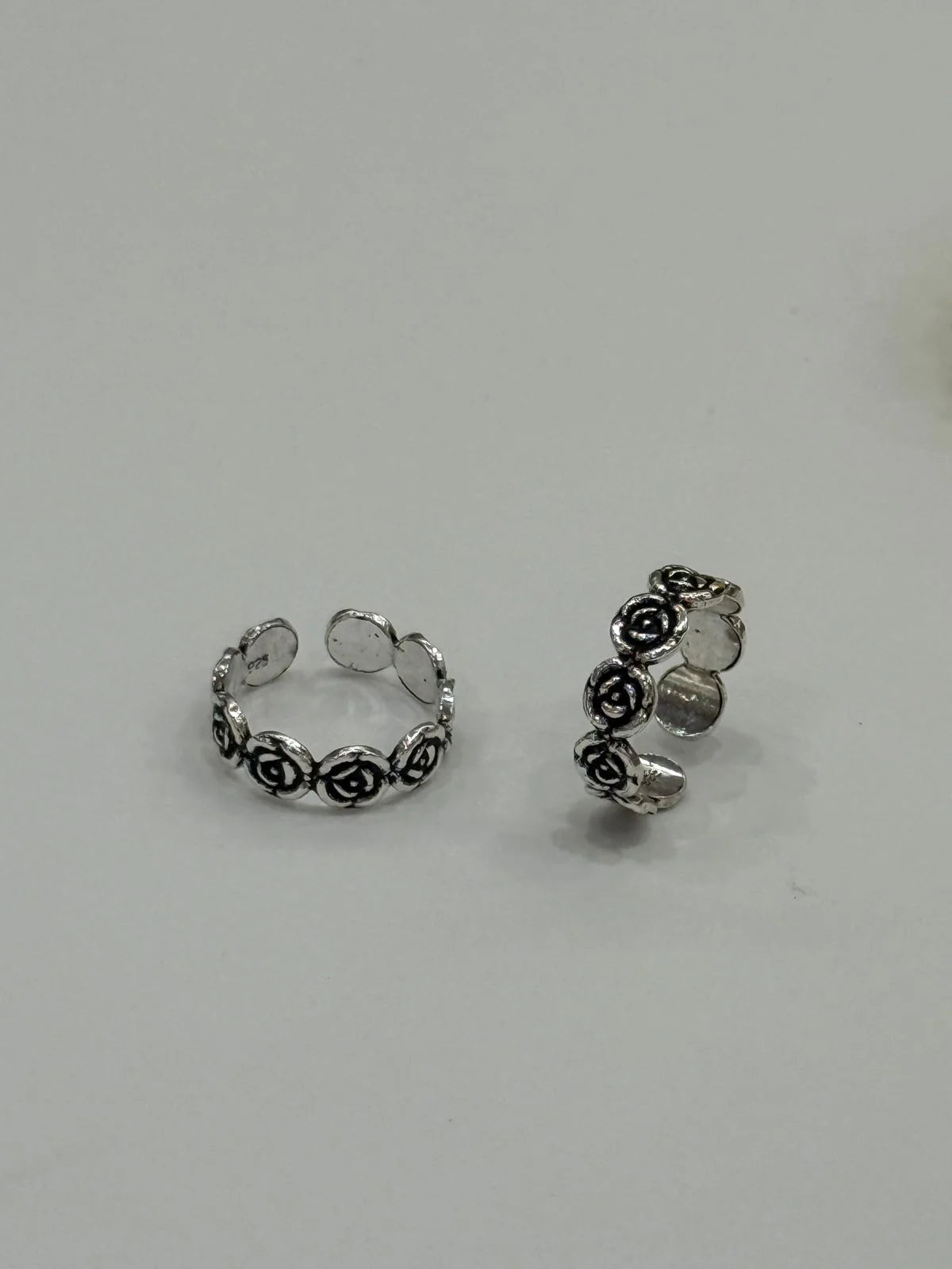 Silver toe rings 
with floral design on a light gray background