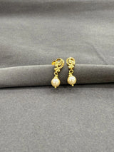 Gold earrings with pearl drops on a gray fabric background