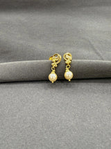 Gold earrings with pearl drops on a gray surface