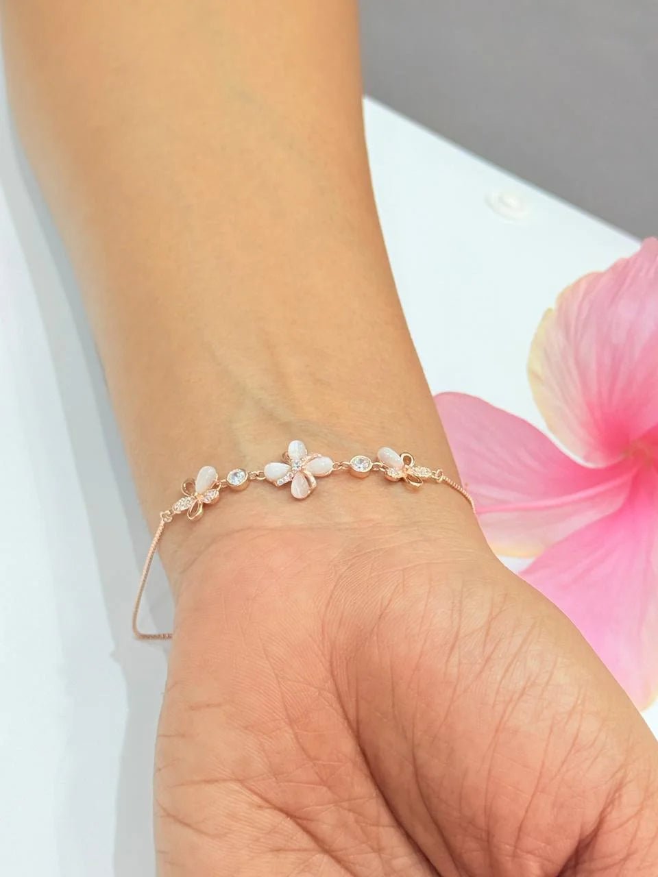 Bracelet with floral designs on a wrist against a pink flower background
