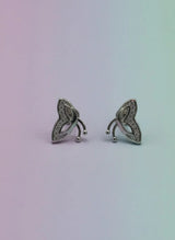 Pair of silver earrings with intricate designs on a gradient background